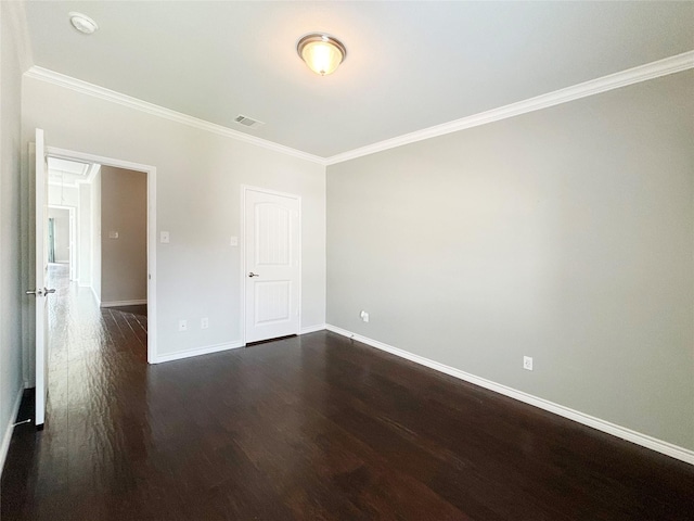 empty room with baseboards, visible vents, dark wood-type flooring, and ornamental molding