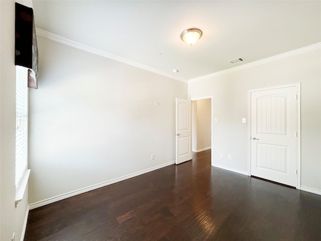 spare room featuring crown molding, dark wood-style flooring, visible vents, and baseboards