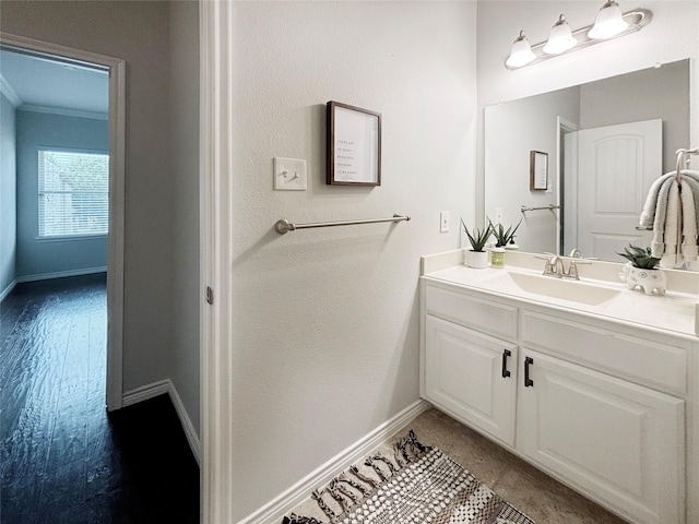 bathroom featuring baseboards, crown molding, and vanity