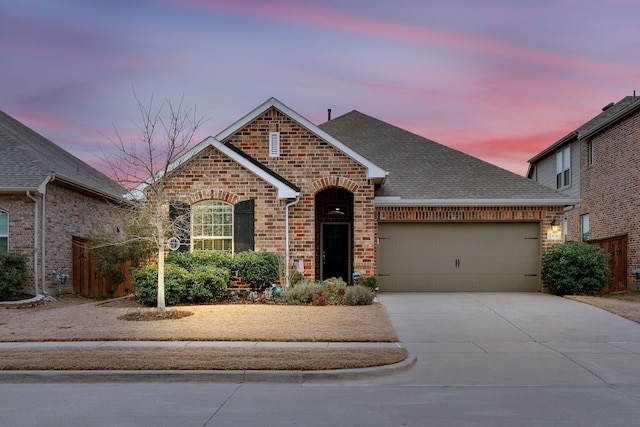 view of front of property featuring a shingled roof, concrete driveway, brick siding, and an attached garage