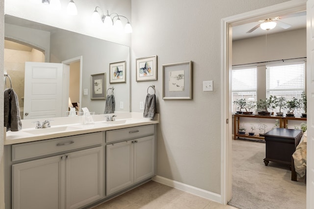 bathroom featuring ceiling fan, a sink, baseboards, and double vanity