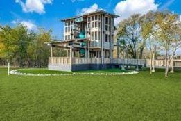 back of property featuring playground community and a lawn