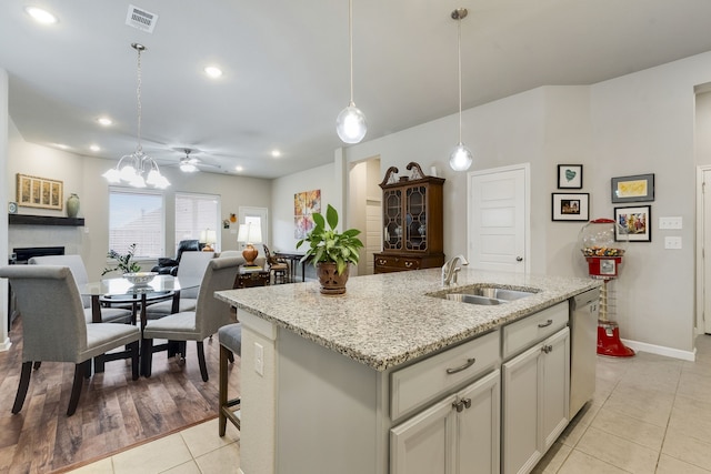 kitchen with visible vents, open floor plan, a kitchen island with sink, a sink, and dishwasher