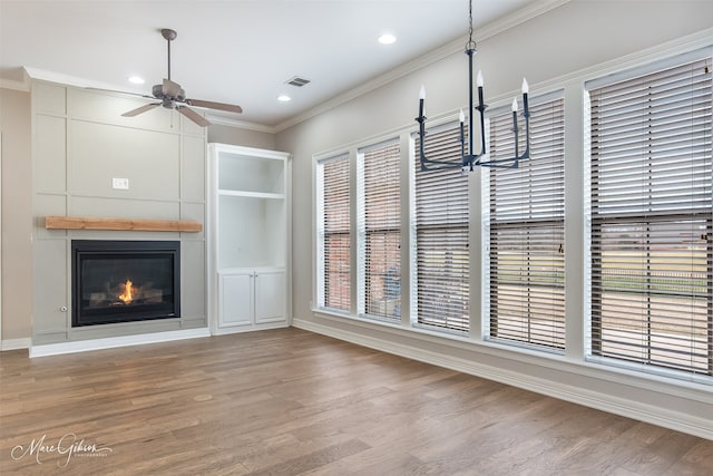 unfurnished dining area with light wood-type flooring, a fireplace, visible vents, and crown molding