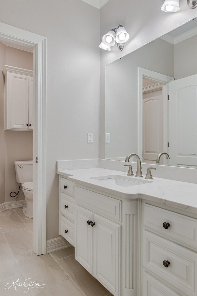 bathroom with baseboards, toilet, ornamental molding, tile patterned floors, and vanity