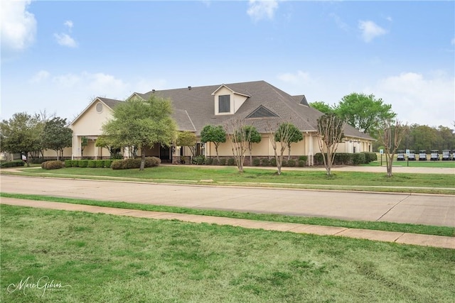 view of front of house with concrete driveway, a front yard, and stucco siding