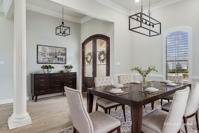 dining space with arched walkways, french doors, crown molding, light wood-style flooring, and ornate columns