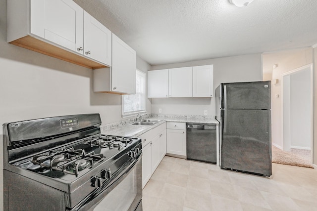 kitchen featuring white cabinets, black appliances, light countertops, and a sink