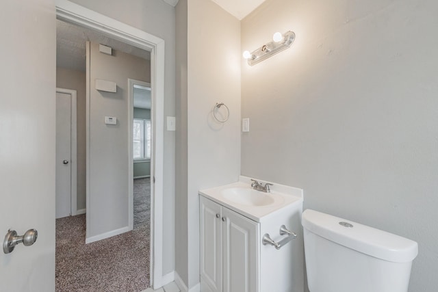 half bath featuring baseboards, vanity, and toilet