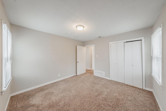 unfurnished bedroom featuring a closet, carpet flooring, visible vents, and baseboards