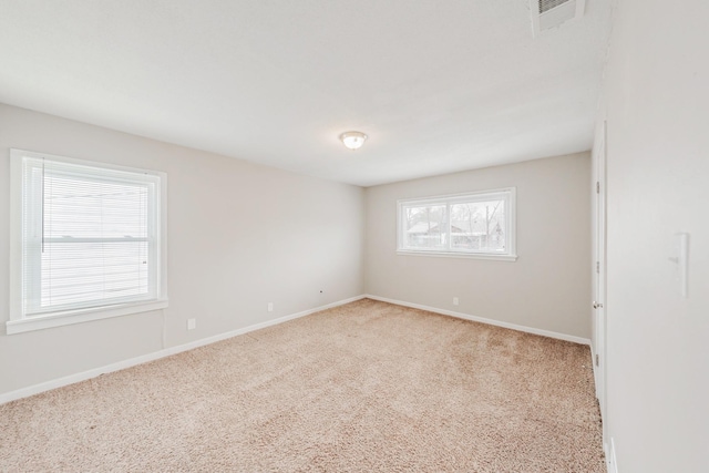 unfurnished room with light carpet, visible vents, and baseboards