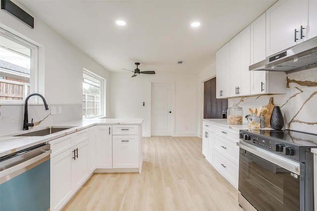 kitchen with a sink, stainless steel appliances, light countertops, and under cabinet range hood