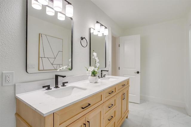 full bath featuring marble finish floor, a sink, baseboards, and double vanity