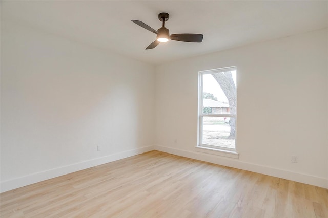 spare room featuring ceiling fan, light wood-type flooring, and baseboards