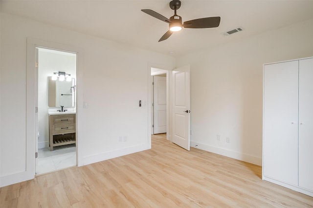 unfurnished bedroom featuring light wood finished floors, baseboards, visible vents, ensuite bathroom, and a sink