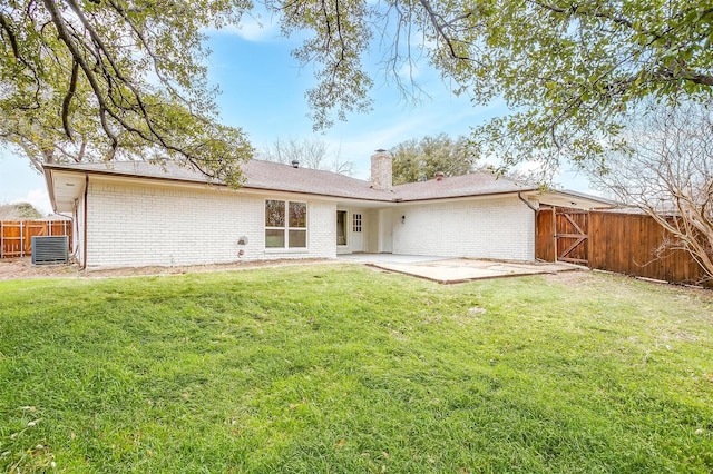 rear view of property with a yard, brick siding, and fence