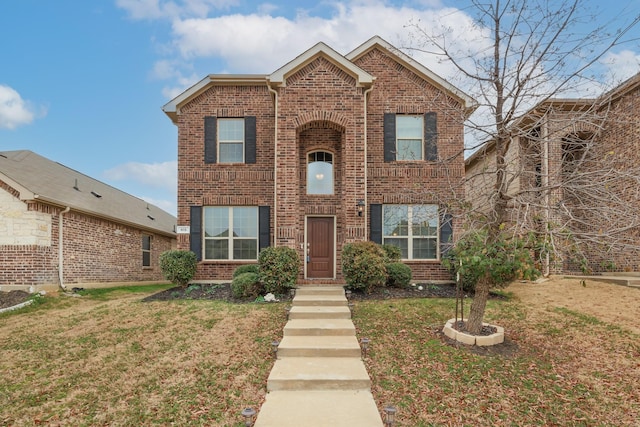 traditional-style house featuring a front yard and brick siding