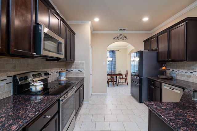 kitchen featuring arched walkways, stainless steel appliances, visible vents, dark stone counters, and crown molding