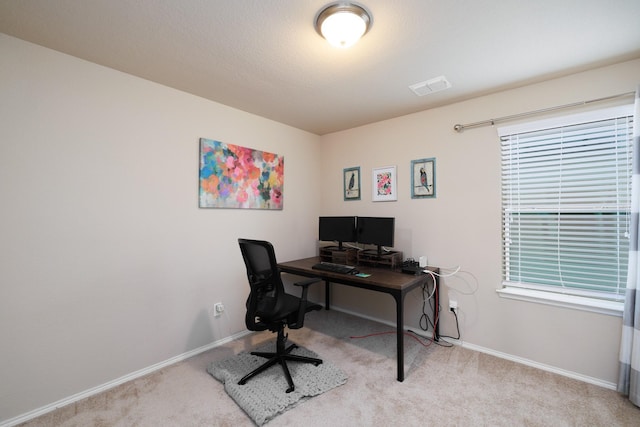 office area with baseboards, visible vents, and light colored carpet