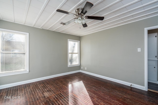 empty room with dark wood-style floors, visible vents, ceiling fan, and baseboards