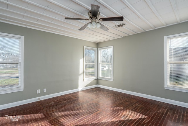 spare room with a wealth of natural light, wood finished floors, visible vents, and baseboards