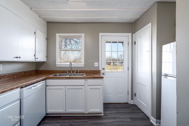 kitchen with white appliances, dark wood finished floors, white cabinets, dark countertops, and a sink