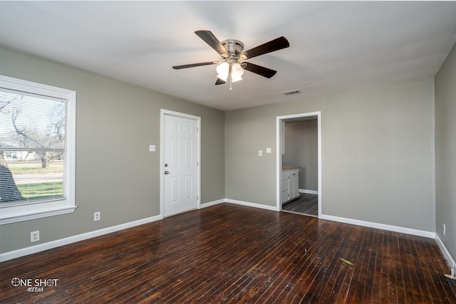 unfurnished room featuring ceiling fan, dark wood finished floors, visible vents, and baseboards