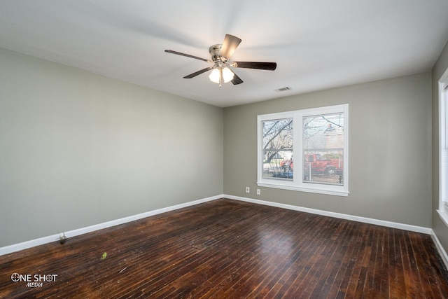 empty room featuring dark wood-style floors, visible vents, baseboards, and a ceiling fan