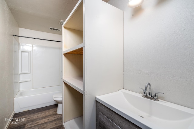 full bathroom featuring visible vents, a textured wall, toilet, wood finished floors, and vanity