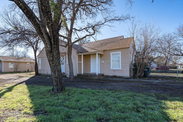 view of front facade featuring a shingled roof and a front yard