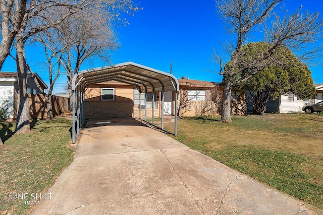 view of front of house featuring brick siding, fence, driveway, a detached carport, and a front yard