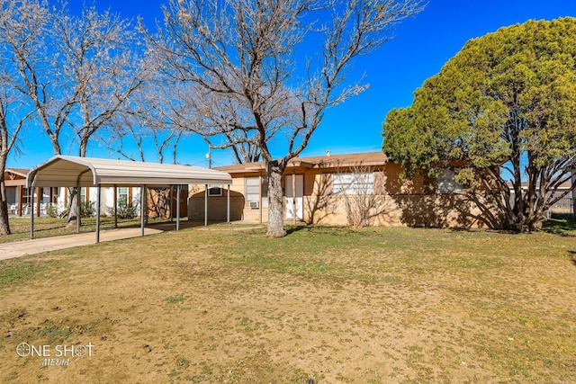 ranch-style home featuring a carport, a front yard, brick siding, and driveway