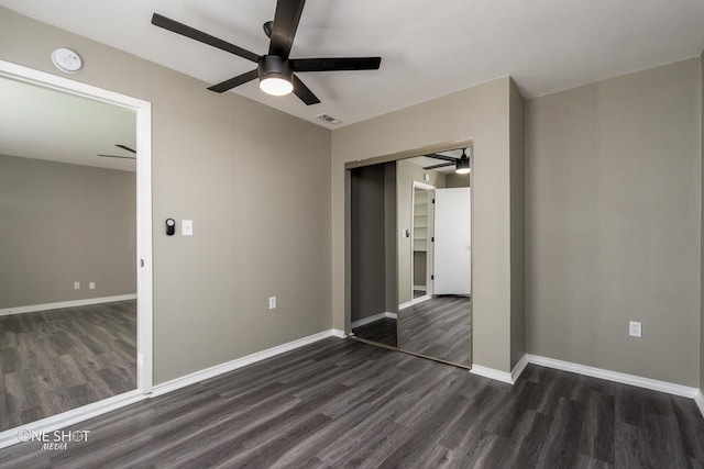 unfurnished bedroom featuring dark wood-style floors, a closet, visible vents, and baseboards