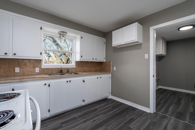 kitchen with tasteful backsplash, baseboards, tile countertops, white cabinetry, and a sink