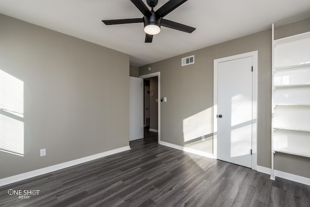 empty room with a ceiling fan, visible vents, baseboards, and dark wood-style flooring