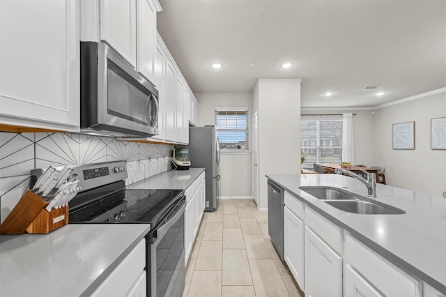 kitchen with stainless steel appliances, light countertops, backsplash, white cabinetry, and a sink