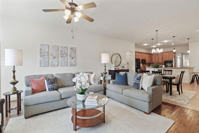 living room featuring light wood-style flooring and ceiling fan with notable chandelier