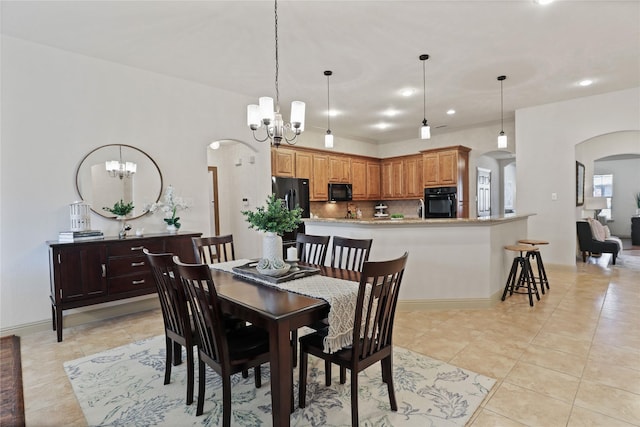 dining space featuring a chandelier, arched walkways, recessed lighting, and light tile patterned floors