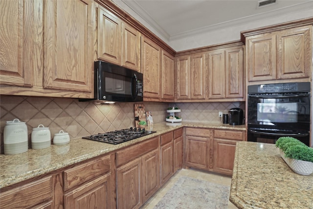 kitchen featuring light stone counters, visible vents, ornamental molding, decorative backsplash, and black appliances