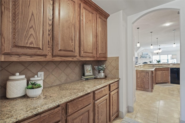 kitchen featuring dishwasher, brown cabinetry, arched walkways, and a sink