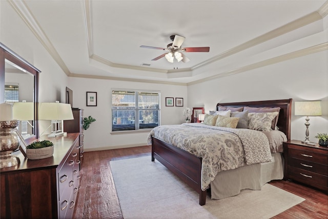 bedroom featuring dark wood-style floors, a raised ceiling, ornamental molding, and baseboards