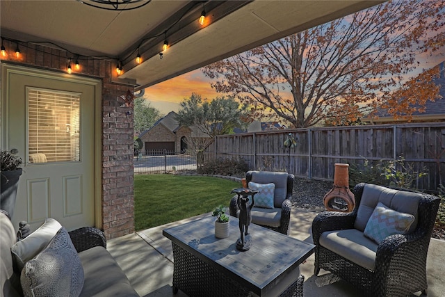 patio terrace at dusk featuring a fenced backyard, an outdoor hangout area, and a yard