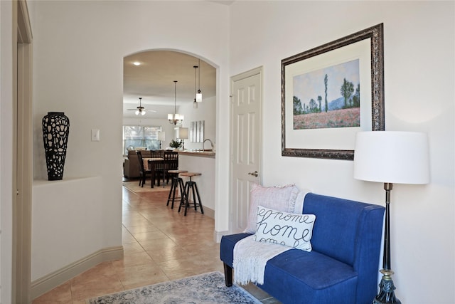 sitting room with light tile patterned floors, baseboards, and arched walkways