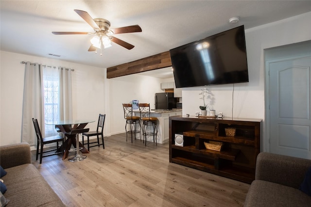 dining area featuring light wood finished floors, beam ceiling, visible vents, and a ceiling fan