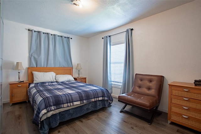 bedroom featuring a textured ceiling, wood finished floors, and baseboards