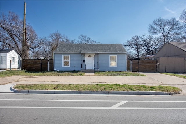 view of front of home featuring roof with shingles and fence