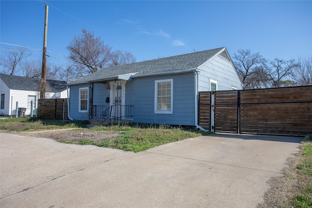 view of front of house featuring a gate, roof with shingles, and fence