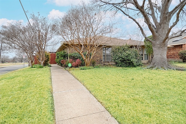 ranch-style house featuring a front yard and brick siding