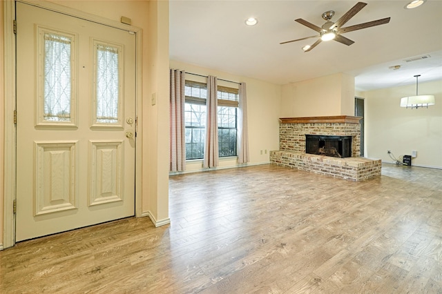 unfurnished living room with light wood-style floors, visible vents, a fireplace, and ceiling fan