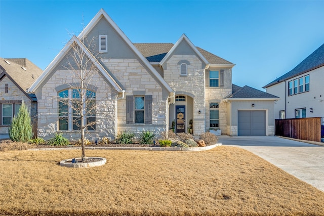 french country home with a garage, driveway, stone siding, roof with shingles, and a front lawn